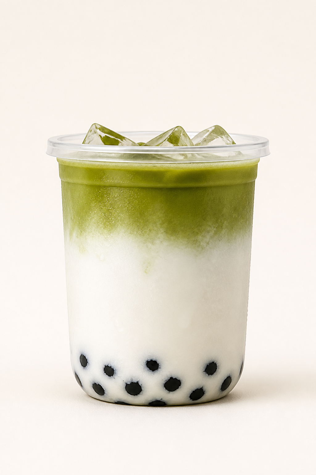 Breiter Becher Matcha Latte, grün über Milch geschichtet, mit schwarzen Tapiokaperlen.