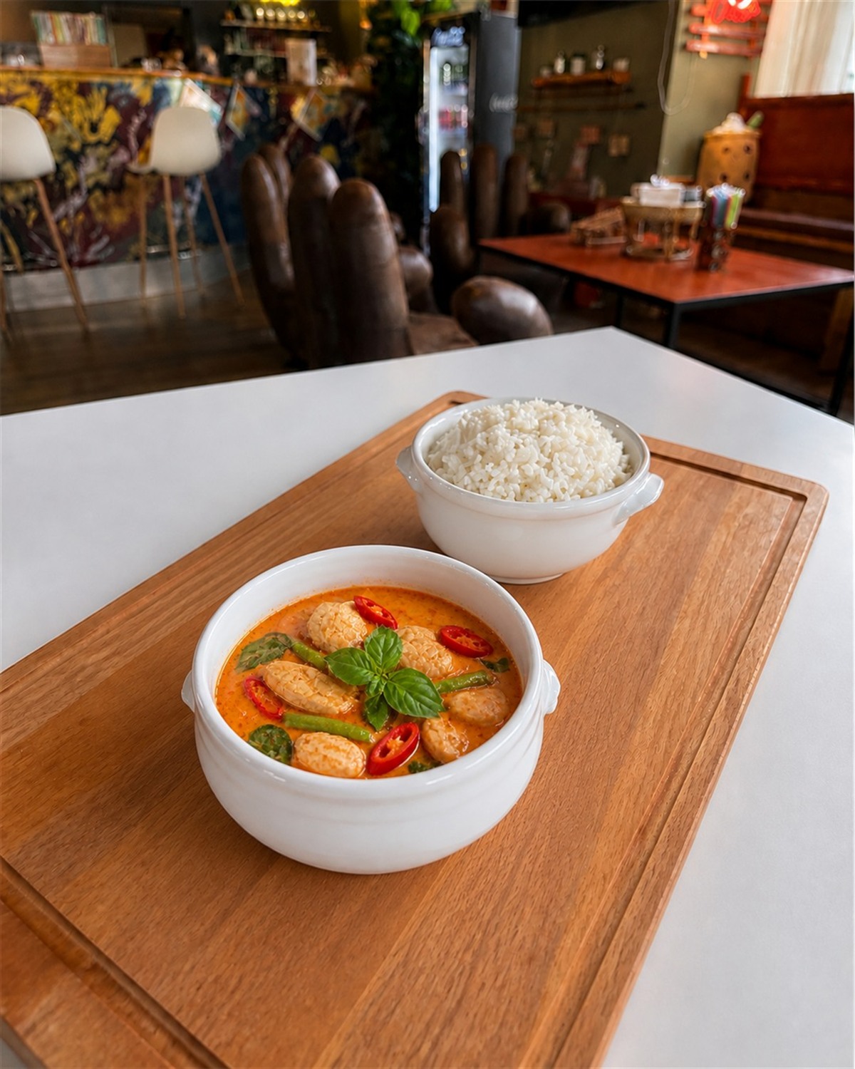 Red Curry Poulet in einer weissen Keramikschale mit Jasminreis in einer separaten weissen Schale