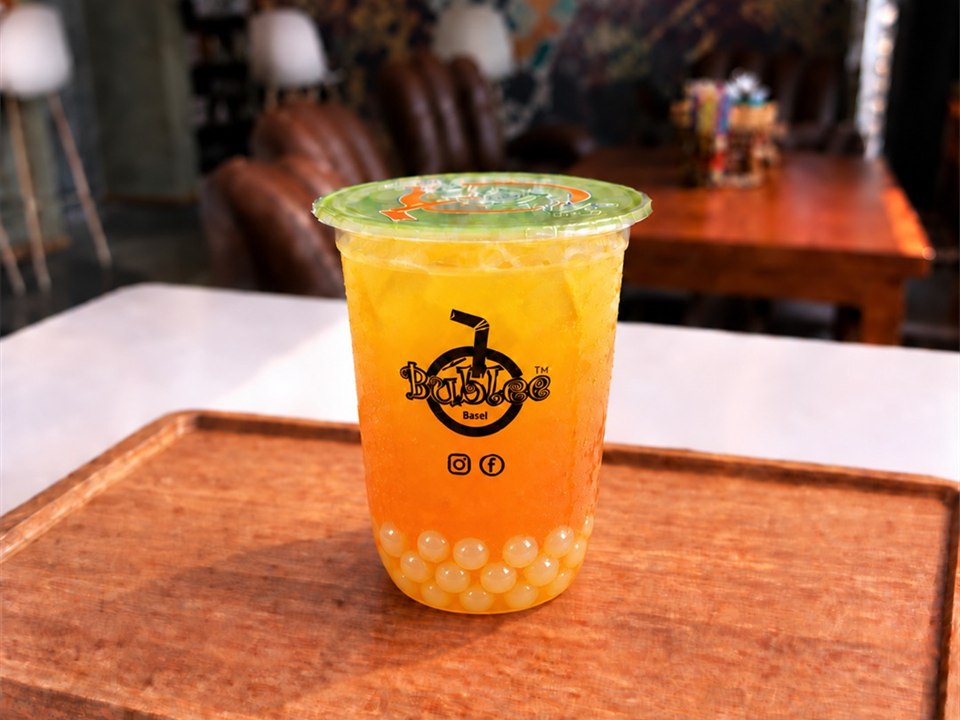 Bublee Mango Tea with translucent white lychee popping boba in a sealed cup.