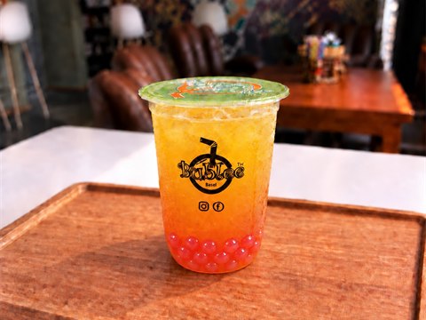 Bublee Passion Fruit Tea with translucent red strawberry popping boba in a sealed cup.