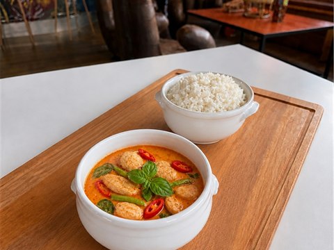 Red Curry chicken in a white ceramic bowl with jasmine rice in a separate white bowl.