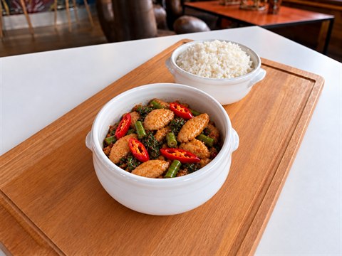 Spicy Basil chicken in a white ceramic bowl with jasmine rice in a separate white bowl.