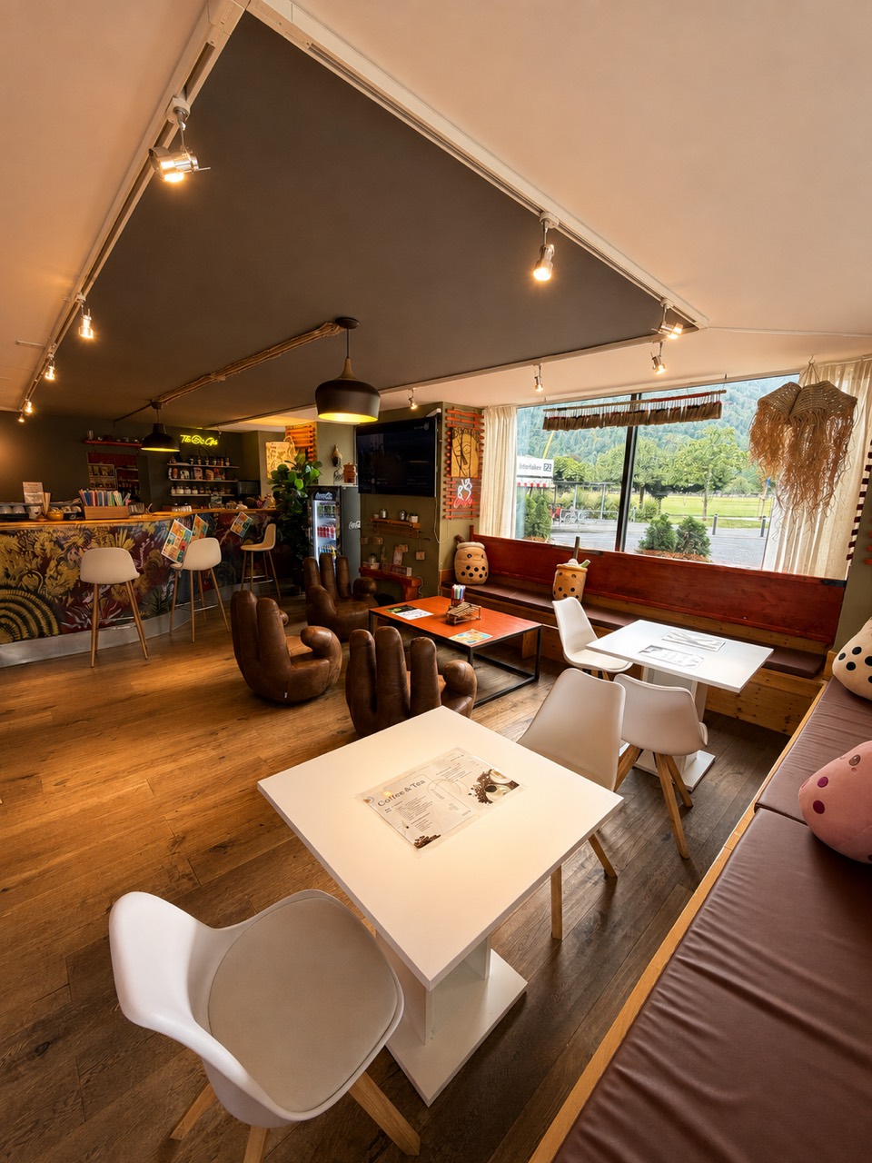 Innenraum des asiatischen Cafés The B's Club im Zentrum von Interlaken mit Tischen, Sitzplätzen und Bergblick